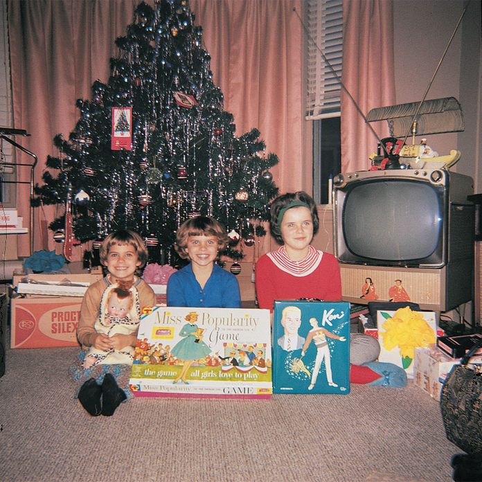 Kids posing in front of Christmas tree and opened presents