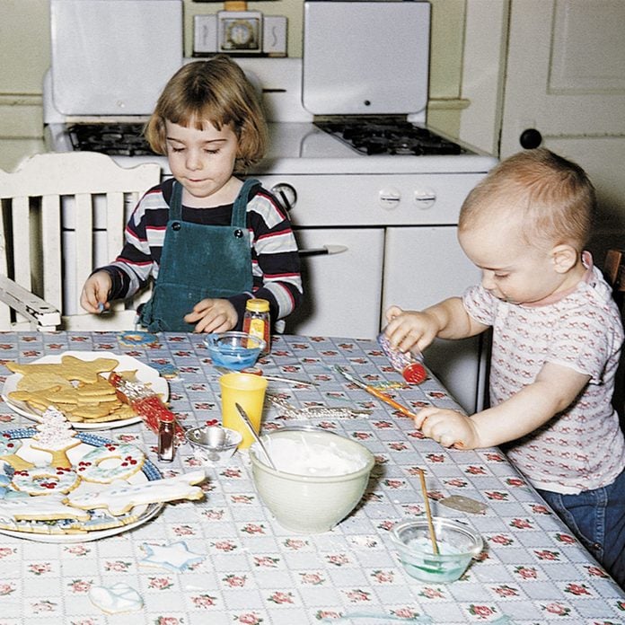 Two young kids decorating Christmas cookies