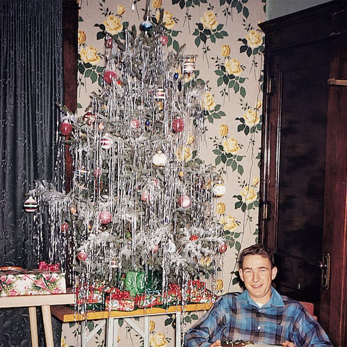 Man reclining in a chair beside a Christmas tree