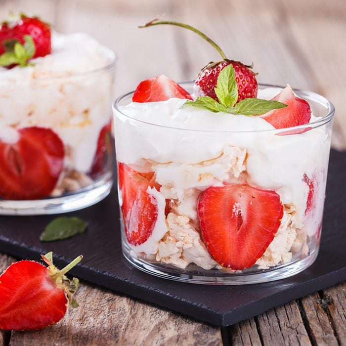 Eton Mess - Strawberries with whipped cream and meringue in a glass beaker.