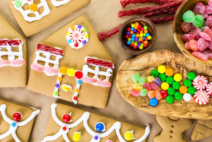Decorating gingerbread house with royal icing and colorful candies.