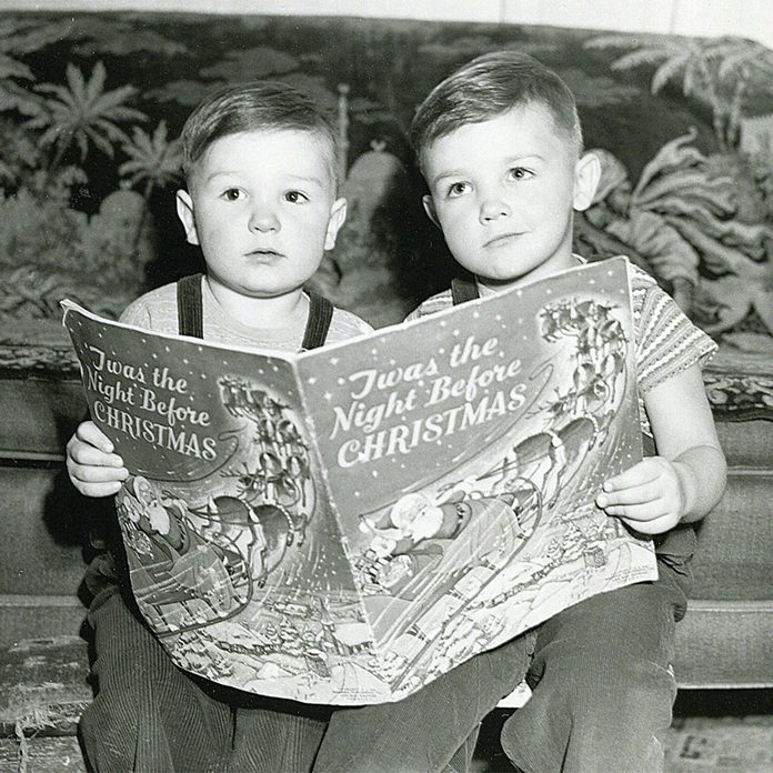 Black and white photo of two children reading a book together