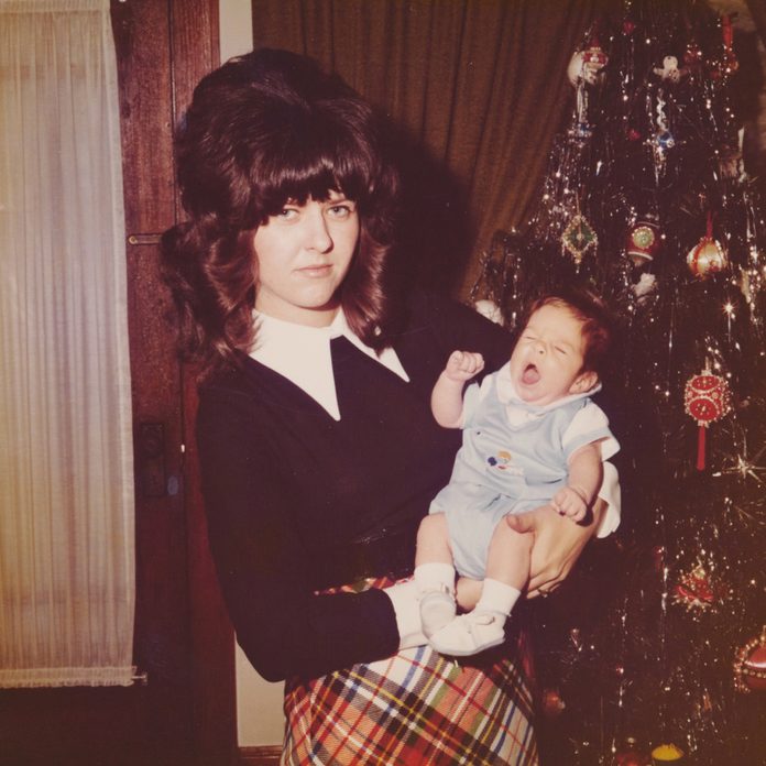 Woman holding a baby in front of a Christmas tree