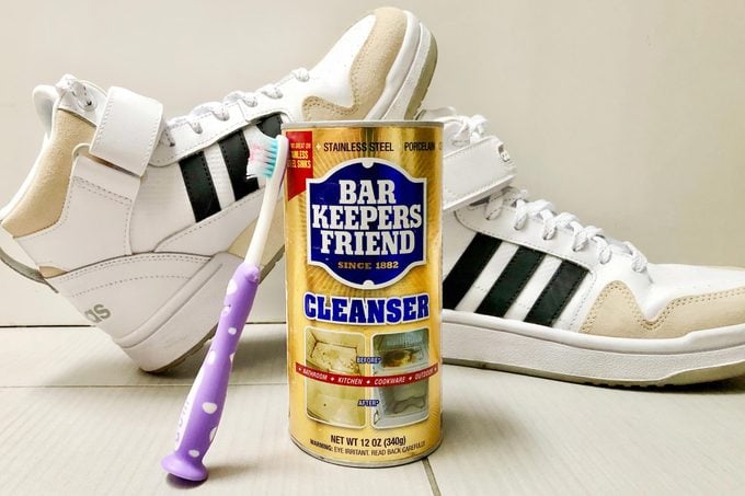 Bar Keepers Friend package and a toothbrush in front of a pair of sneakers