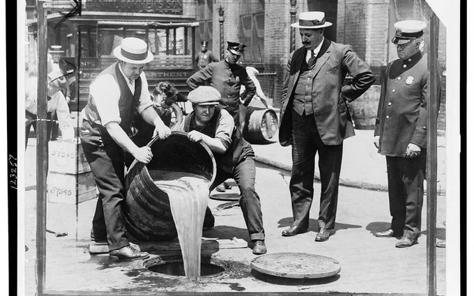 New York City Deputy Police Commissioner John A. Leach, right, watching agents pour liquor into sewer following a raid during the height of prohibition