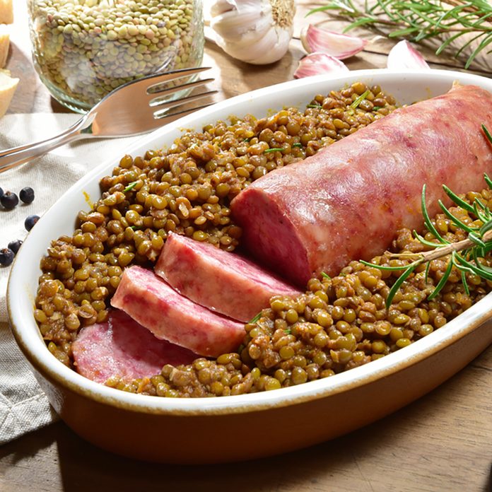 Cotechino with lentils with rosemary served on a plate with some ingredients