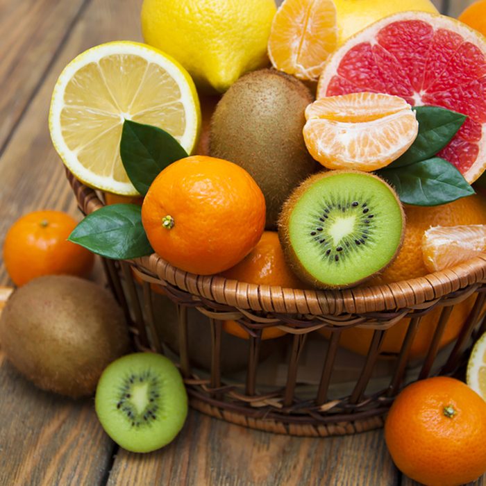 Fresh juicy citrus fruits in a basket on a wooden background