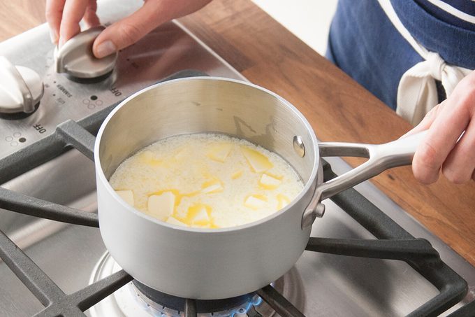 Person melting butter in a pot on the stove