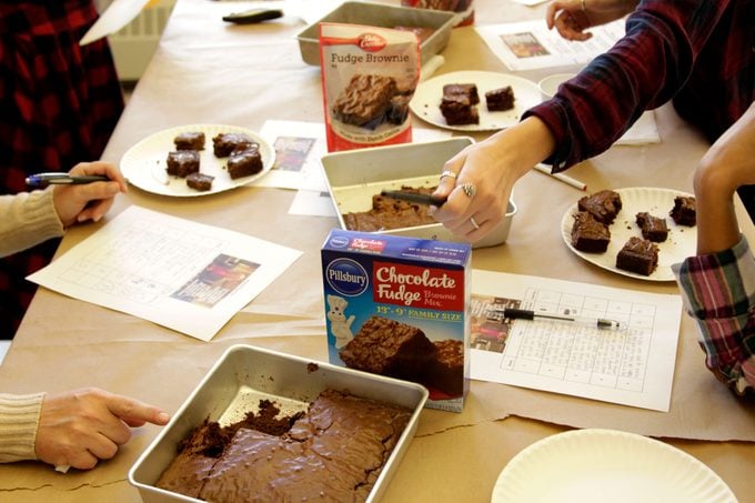 Plates of brownies beside papers and pens as the taste testers dig in