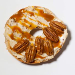 Bagel topped with cream cheese; pecans; caramel sauce