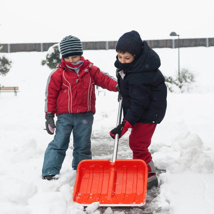 Two children shoveling snow