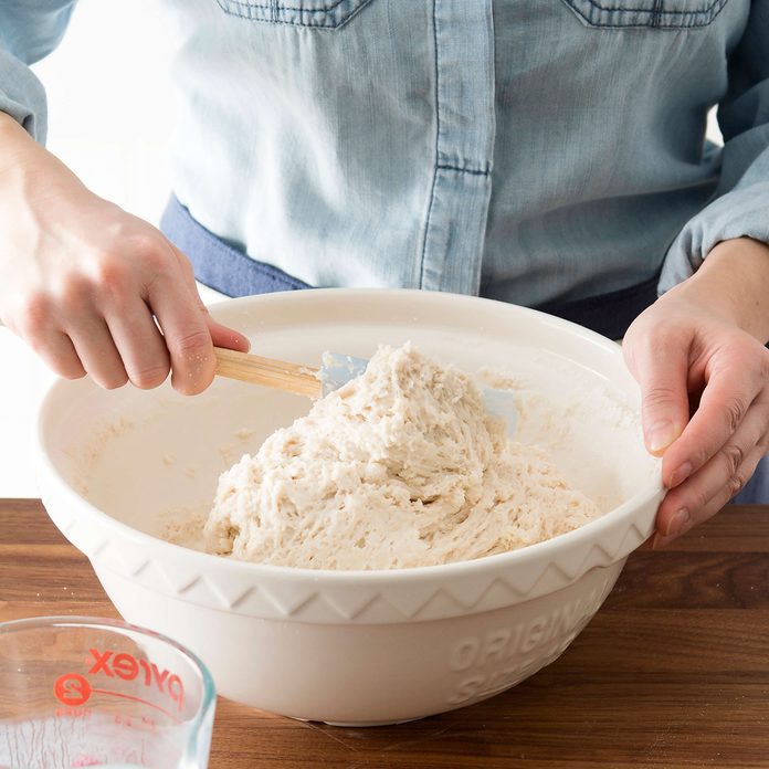 Person using a wooden spoon to mix ingredients in a bowl