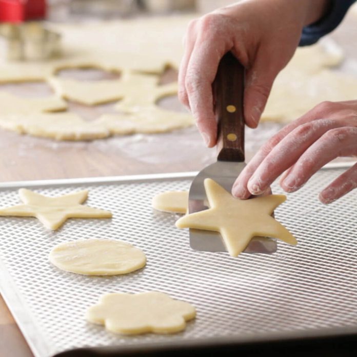 Person using a spatula to pick up sugar cookies