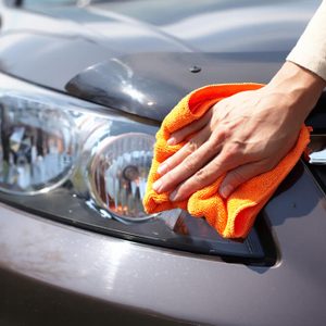 Hand with microfiber cloth cleaning car.