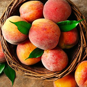 Ripe peaches in basket on wooden background