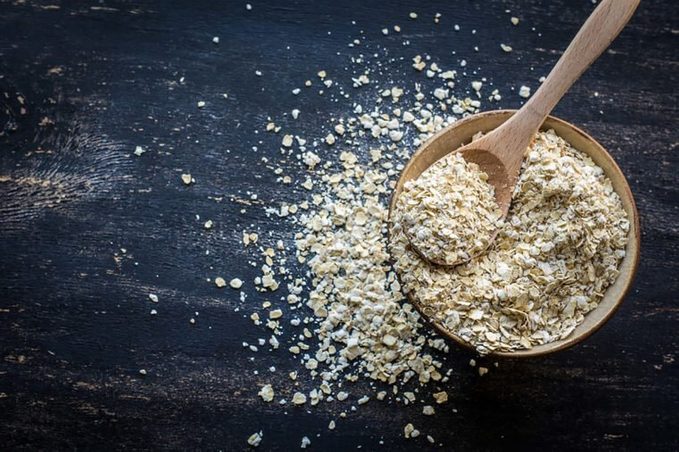 Oats lifted above a bowl in a spoon