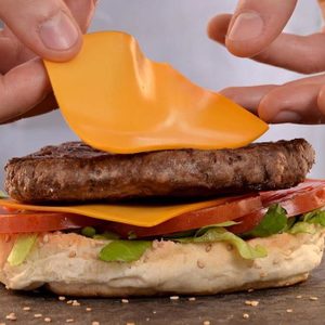 Person putting cheese on a burger