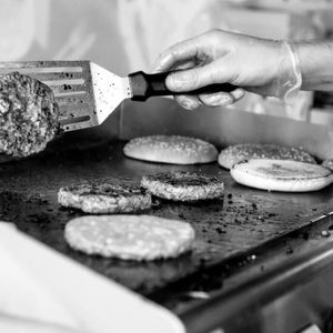 Black and white photo of person grilling burgers