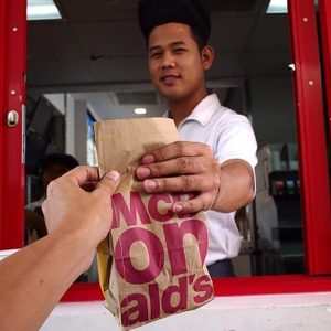 Fast food worker handing a drive-thru customer their bag of food