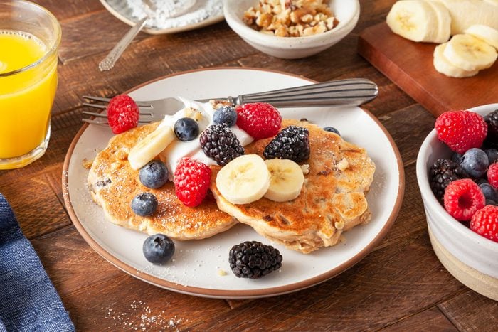 Banana Oatmeal Pancakes Served in a Plate with Topping of Raspberries, Blueberries and Bananas on wooden Surface