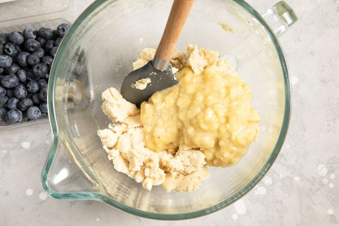 Mashed banana mixed in the cream mixture in a bowl