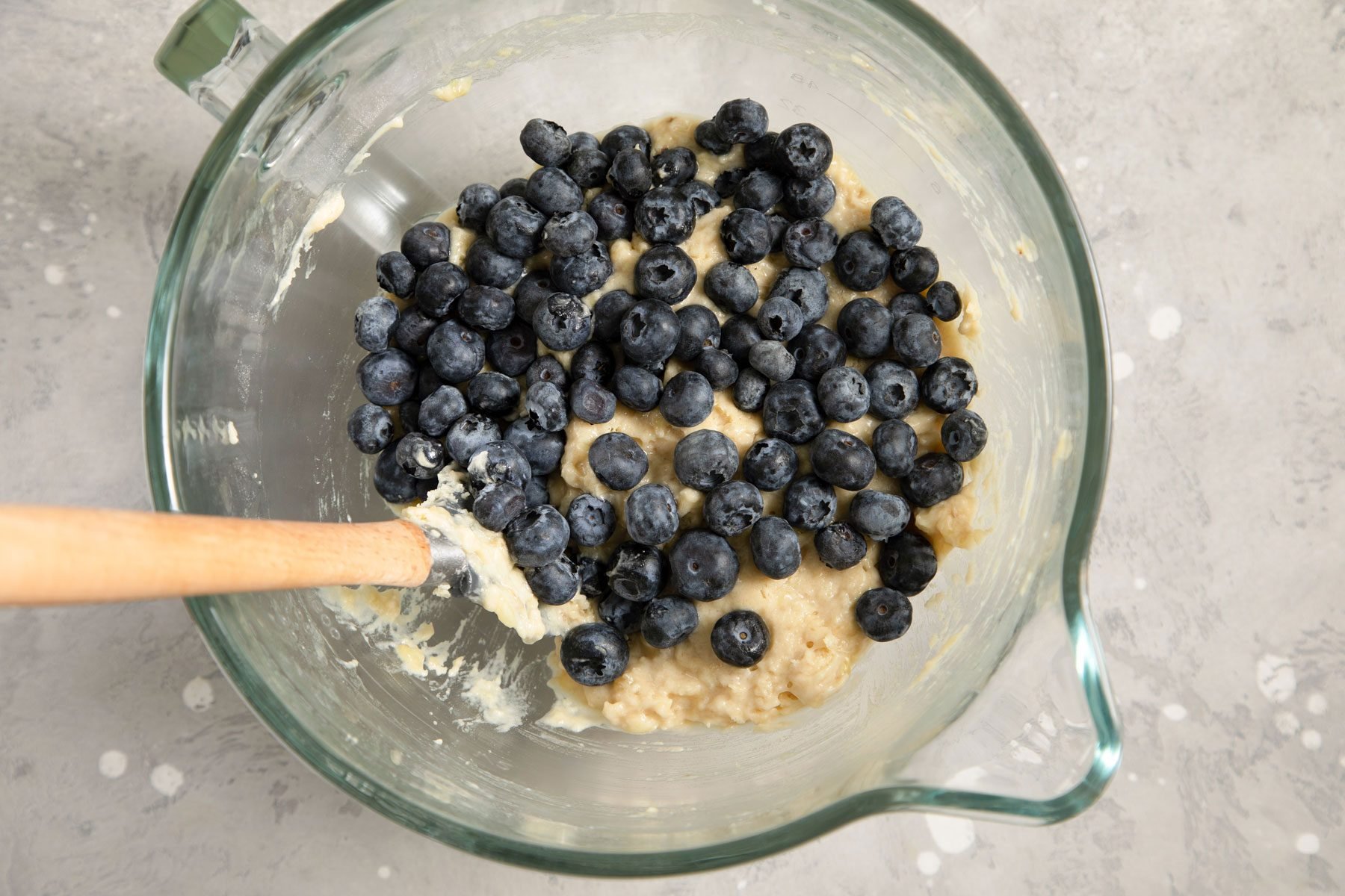 Blueberries mixed in a bowl with a spatula