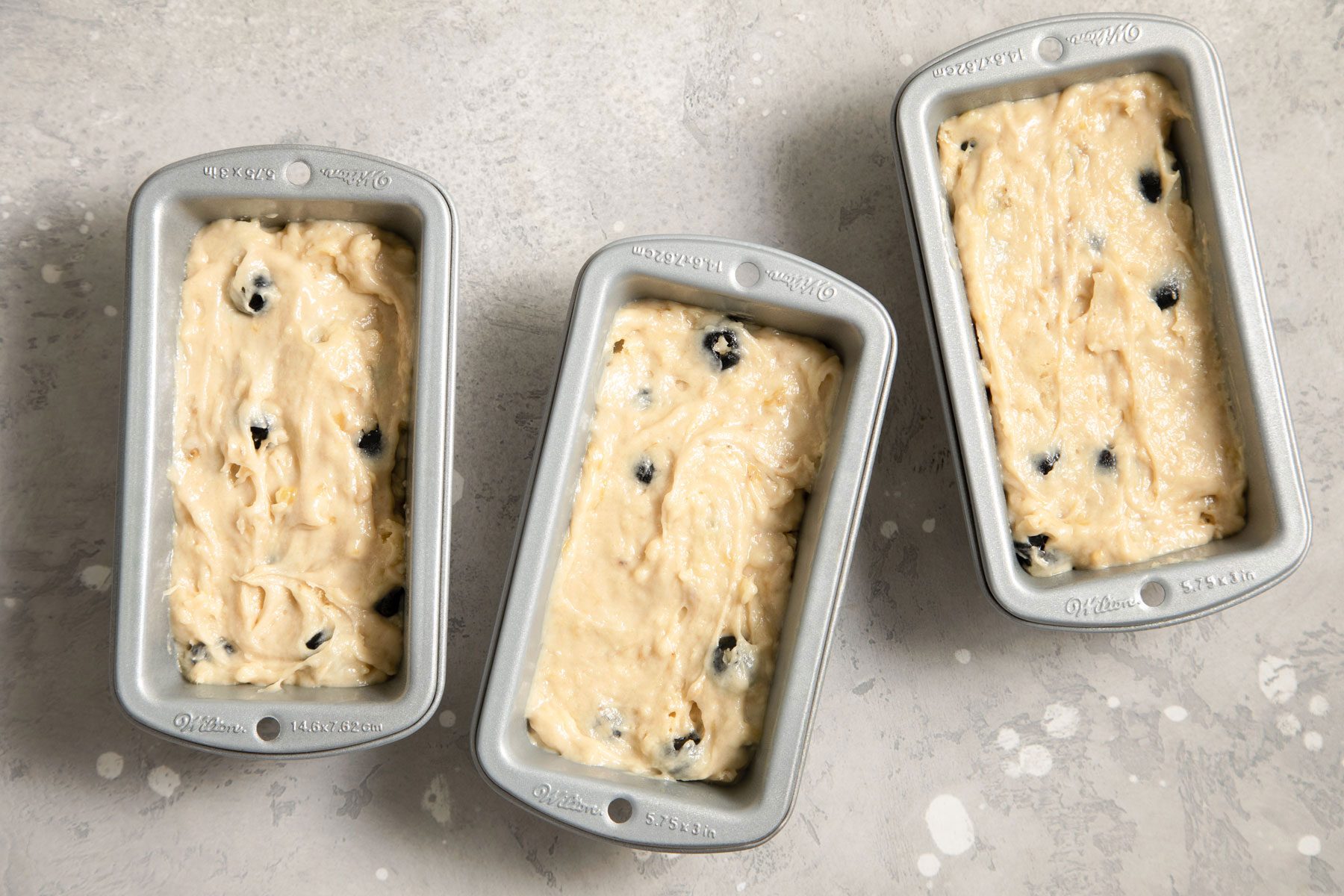 Blueberry Banana Bread batter poured into three greased loaf pans