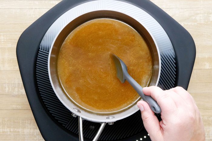 A person cooking sugar and corn syrup in a large sauce pan