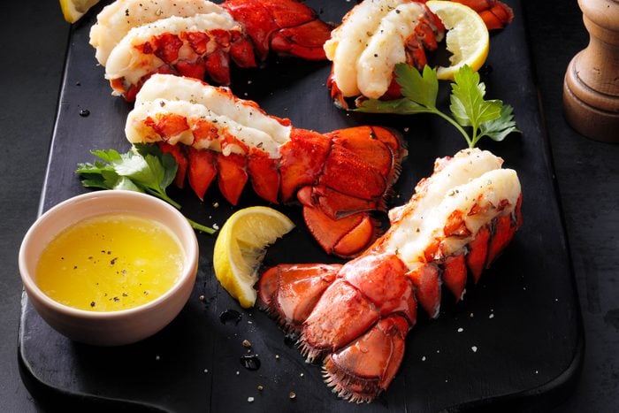 Broiled Lobster Tails with Sliced Lemons on Black Wood Cutting Board