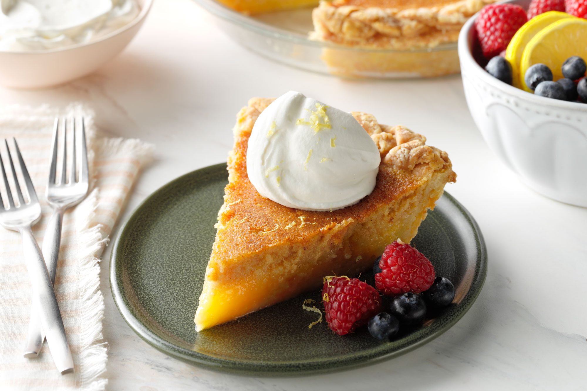 Sliced Buttermilk Pie with whipped cream and fresh berries
