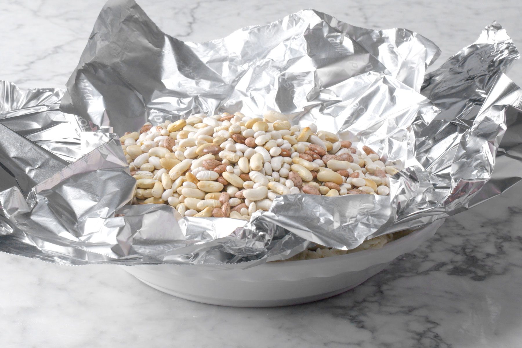 Dried beans spread on foil paper on a bowl