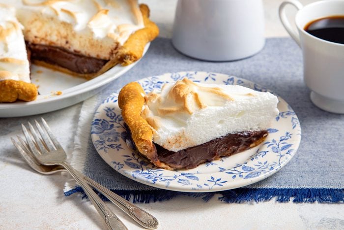 A Slice of Chocolate Meringue Pie Served on a Fancy Ceramic Plate with Forks