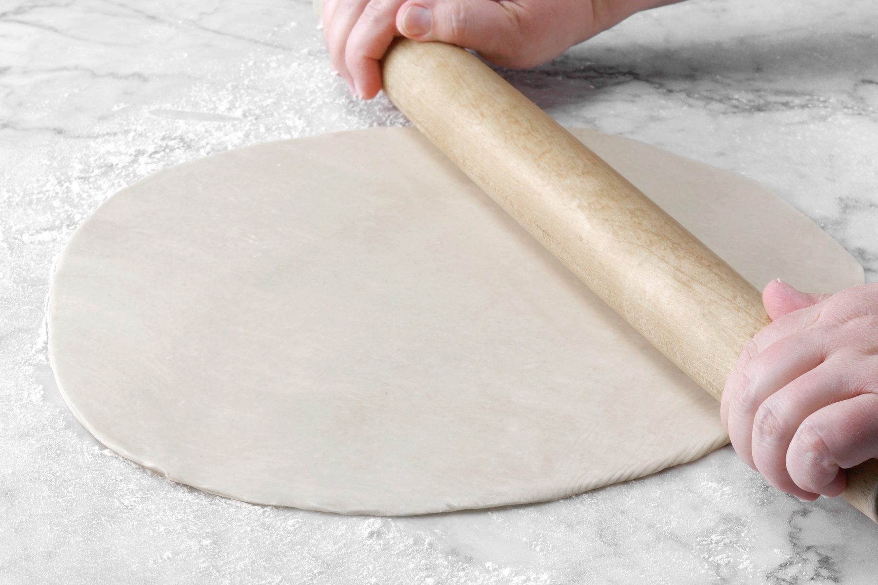 A person rolling out dough with a rolling pin