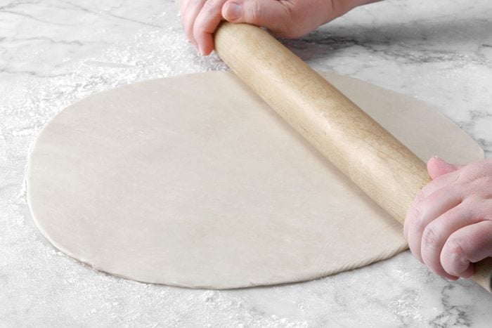 A person rolling out dough with a rolling pin