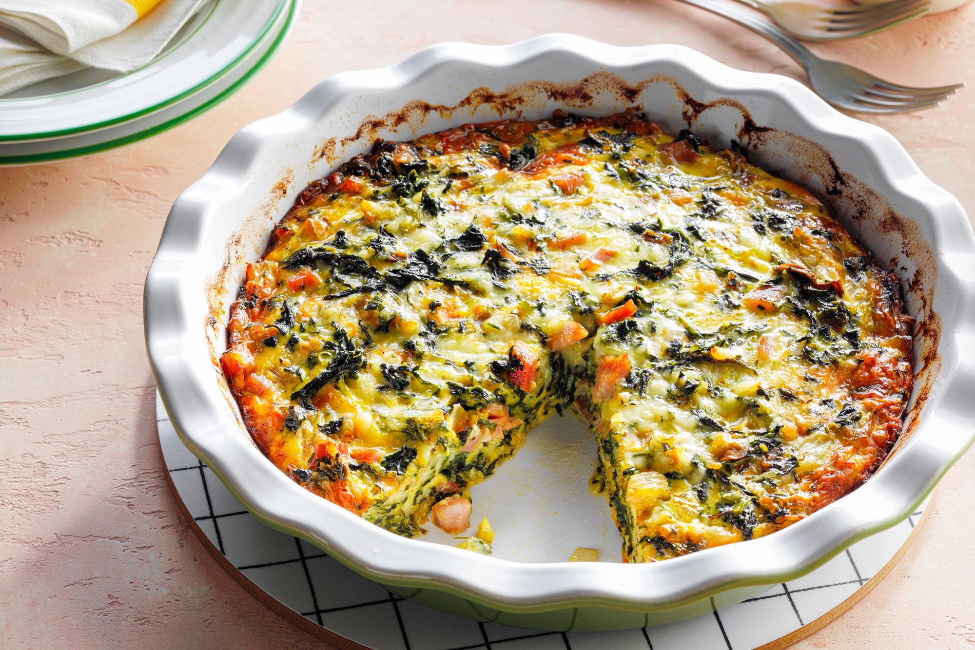 Crustless Spinach Quiche in a Pie Plate on a Light Salmon Background