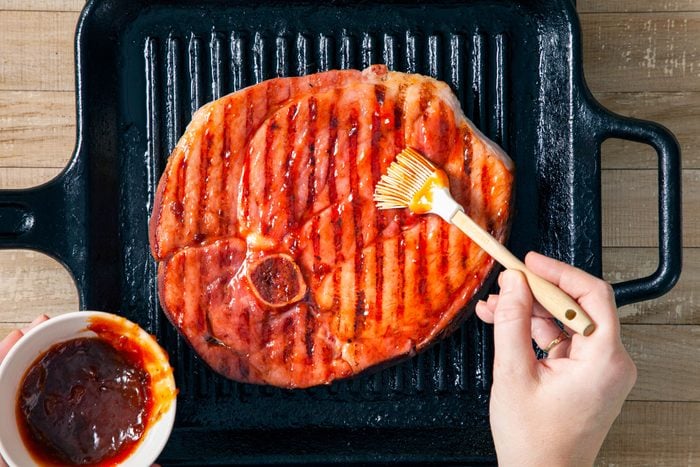 Brushing Ham Steak with Ham Glaze on a Grill Pan on Wooden Surface