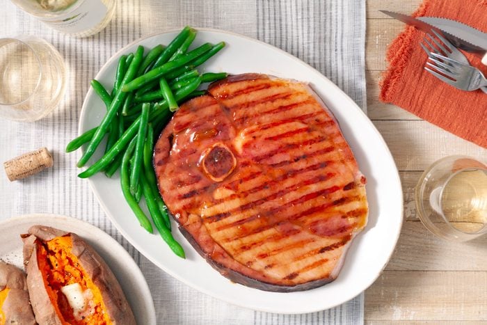 Grilled Ham Steak with Green Beans on a White Oval Shape Plate