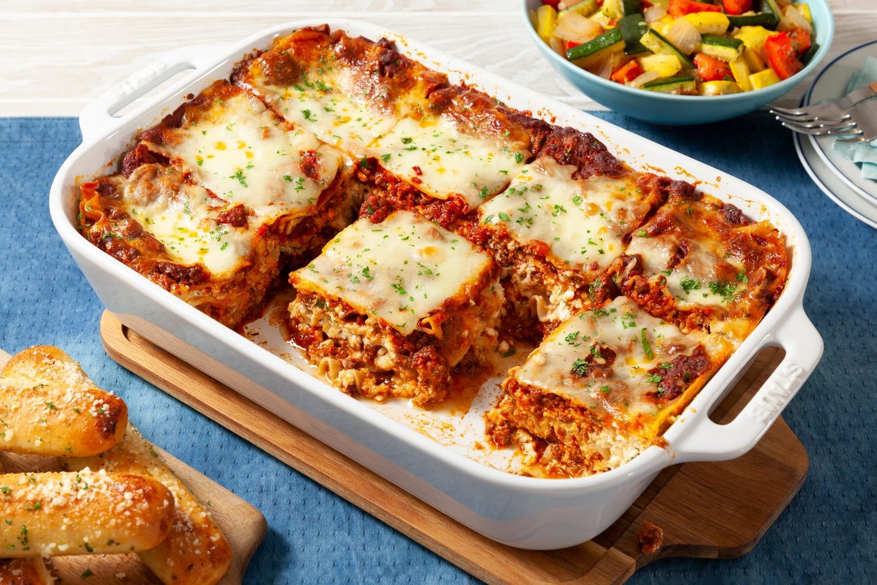 A Casserole Dish With Lasagna and a Bowl of Vegetables
