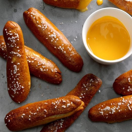 Movie Theater Pretzel Rods and a small cup of dipping sauce on a gray background