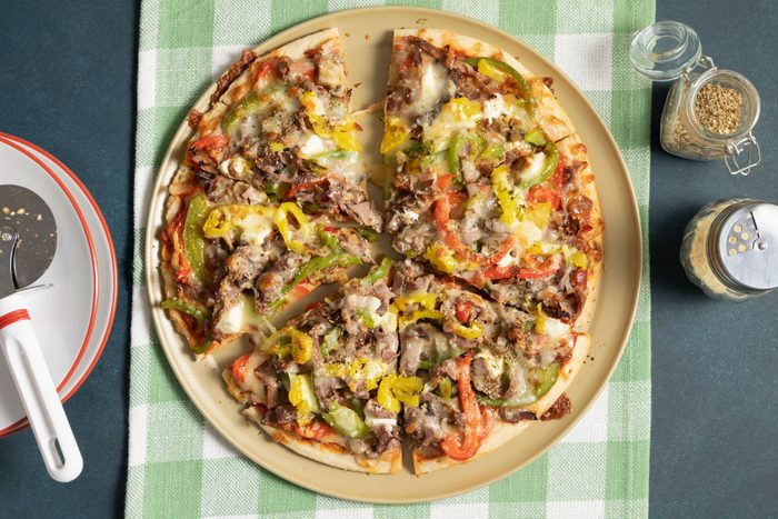 A fully baked Philly Cheesesteak Pizza served on a plate