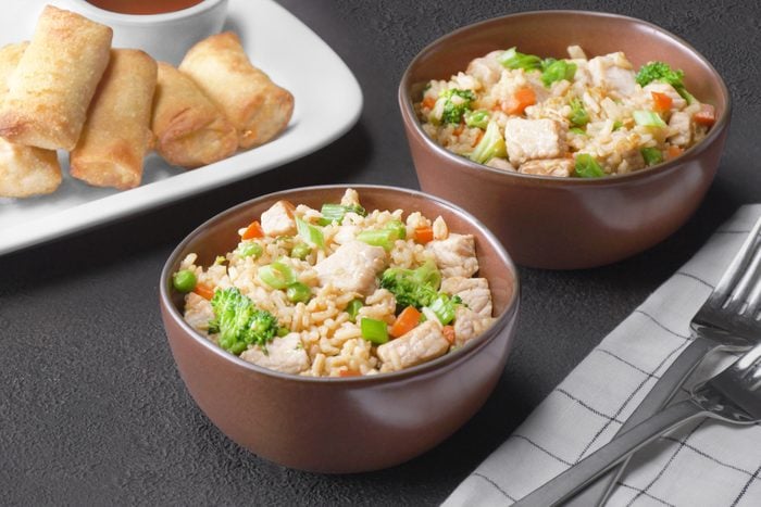 Two bowls of rice with chicken and vegetables on a table.