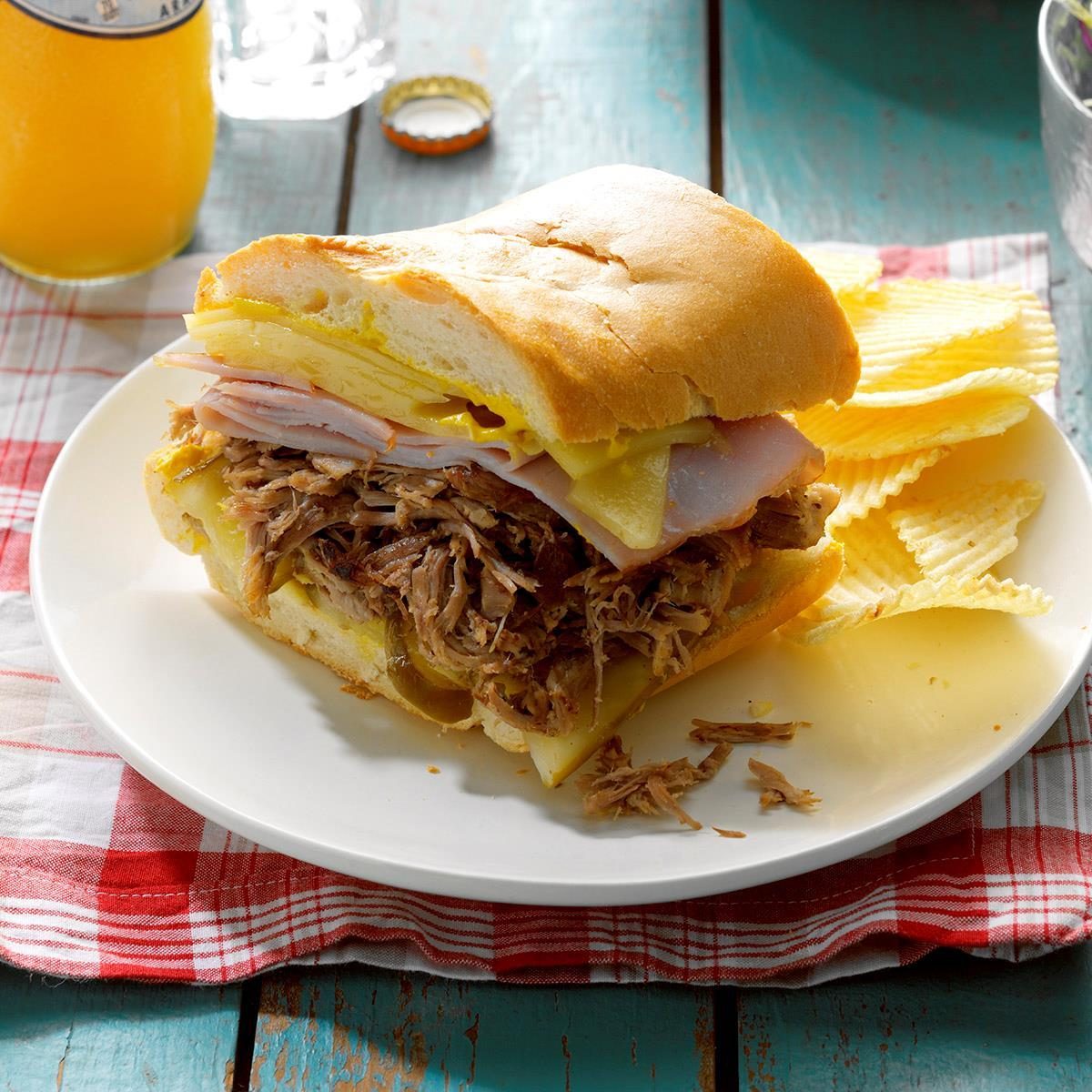 Pressure Cooker Cuban Pulled Pork Sandwiches on a plate with chips on a red checkered napkin