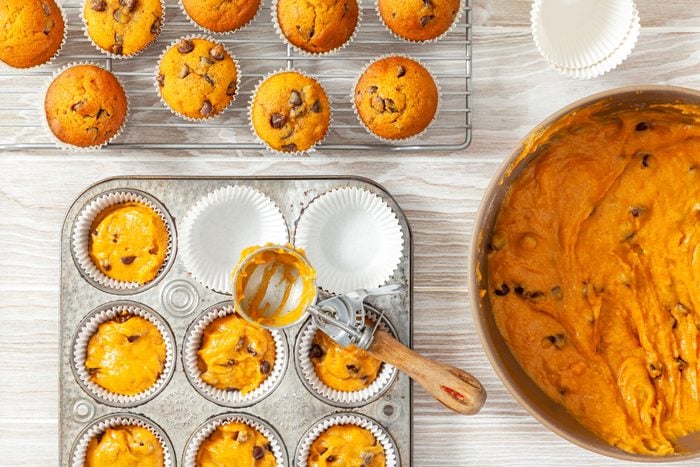 Filling Paper-Lined Muffin Cups with Pumpkin Chocolate Chip Muffins Mixture