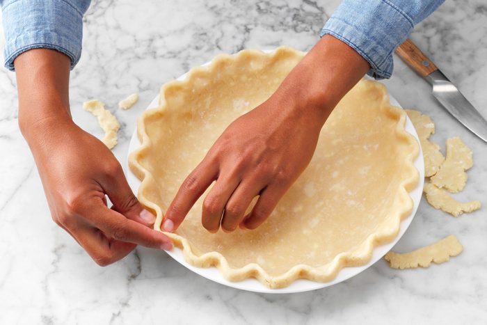 A Person's Hands Touching a Pie Crust