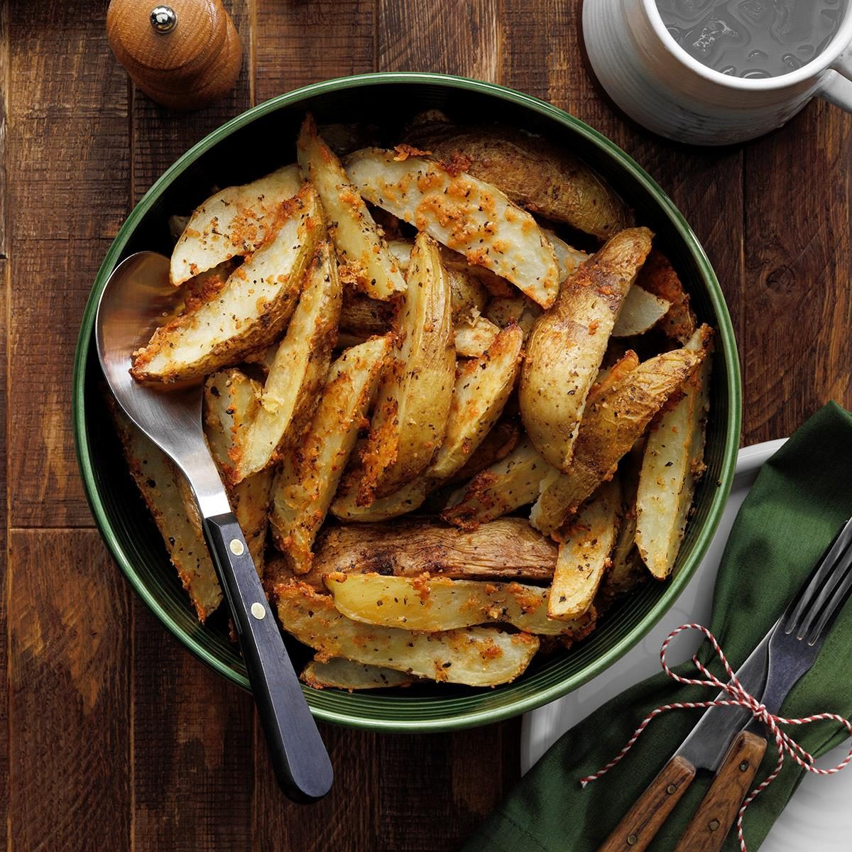 Roasted Parmesan Potato Wedges with a serving spoon on a wood table