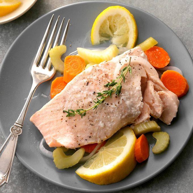 Poached salmon on a plate with citrus and carrots.