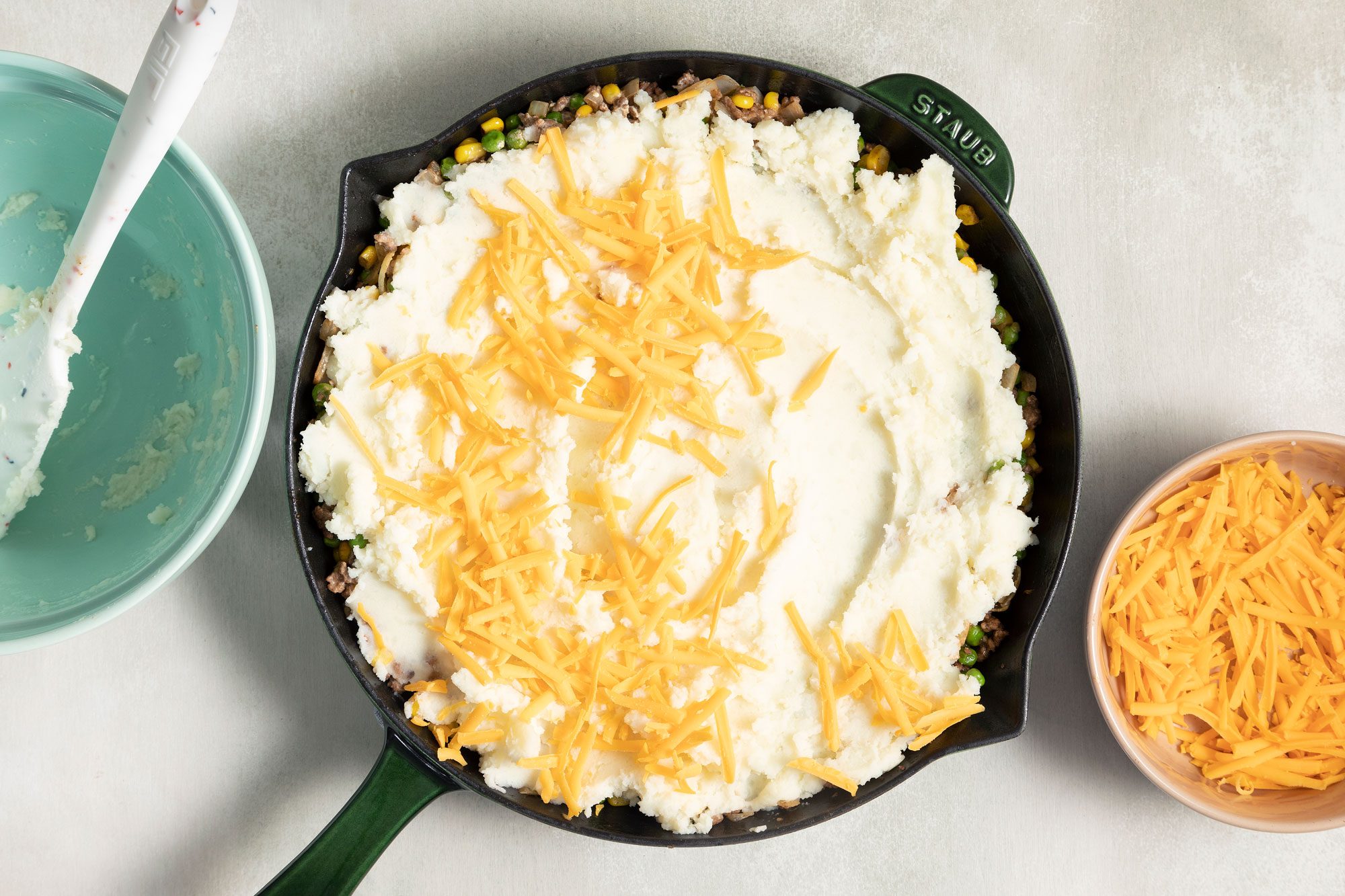 shredded cheese on creamy mashed potatoes in a large skillet