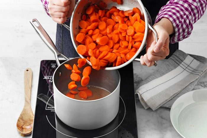 A Person Pouring Carrots Into a Pot