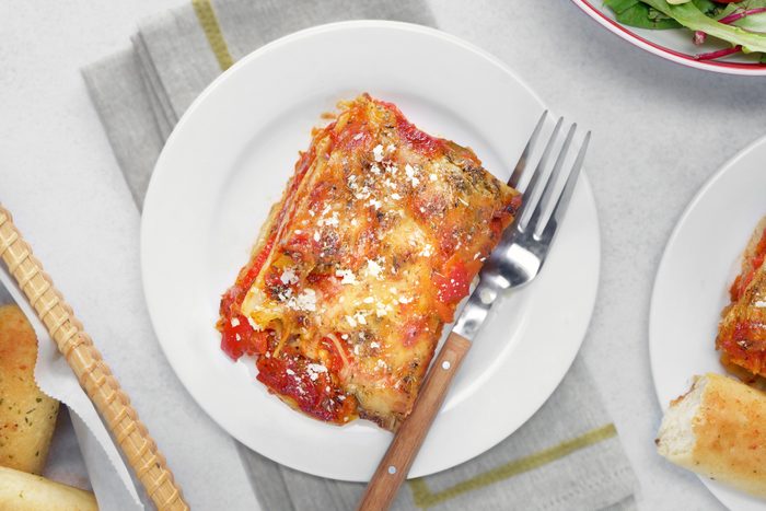 A plate of lasagna with a fork and salad