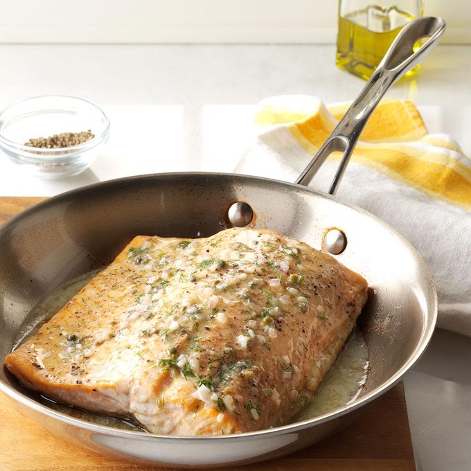 Oven-roasted salmon cooked in a hot skillet.